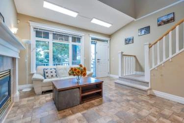 Sun filled living room with high ceiling and gas fireplace.