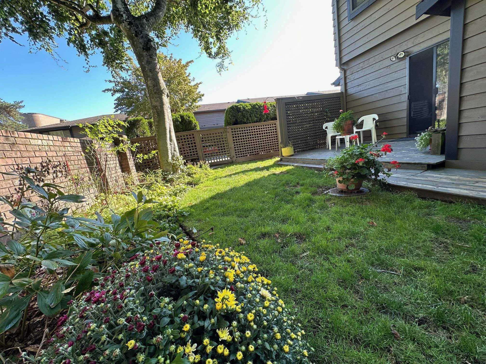 The fully fenced backyard wraps around to the front of the unit. You will love the combination of sun deck, grass and flower beds.